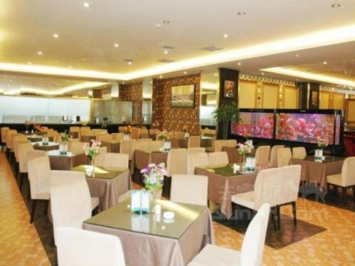 a restaurant with tables and white chairs and a buffet at Aksu Pudong Holiday Hotel in Aksu