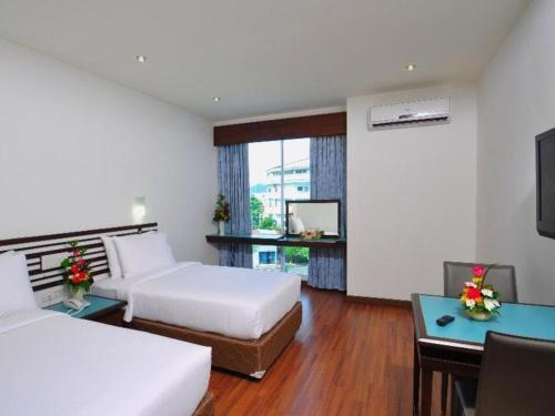 ハジャイにあるThe Color Hotelのベッド2台とデスクが備わるホテルルームです。