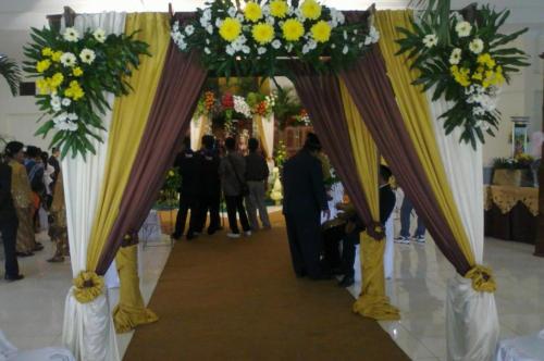 a wedding arch with yellow and white flowers at King Hotel in Bendungan