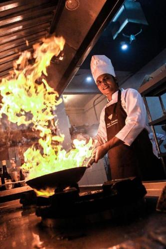 a chef preparing food in a grill in a kitchen at Mega Permata Hotel in Padangsidimpuan