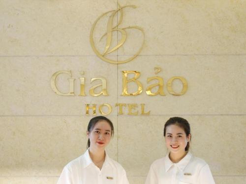 two girls in white uniforms standing in front of a sign at Gia Bao Hotel Bac Ninh in Hanoi