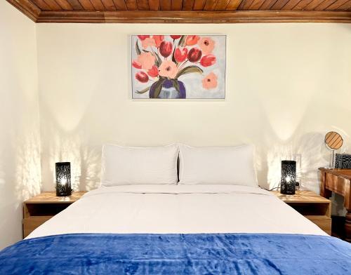 a bedroom with a bed and two lamps and a painting at Opoho Heritage Guest Suite in Dunedin