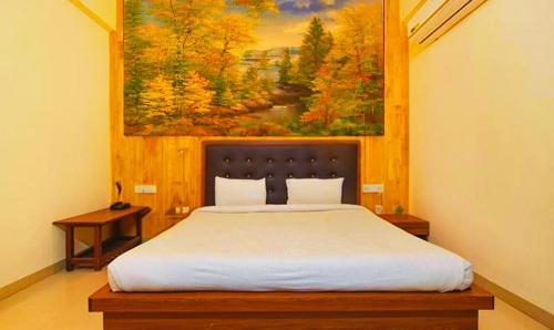a bedroom with a bed with a painting on the wall at Hotel Shubhshree in Indore