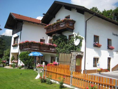 ein weißes Haus mit Blumenkästen und einem Zaun in der Unterkunft Gästehaus Sonnenheim in Thaur