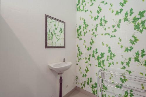 La salle de bains est pourvue d'un lavabo et de feuilles vertes sur le mur. dans l'établissement Omah Nusa Villa RedPartner, à Nusa Penida