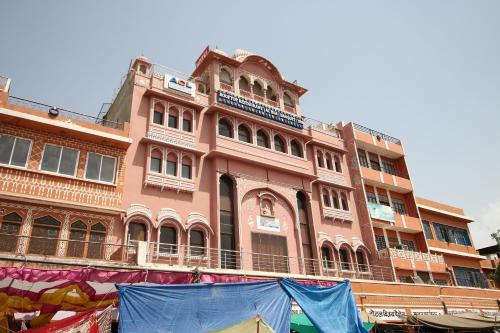 a pink building with a balcony on top of it at Collection O Hotel Vijay Palace in Jaipur