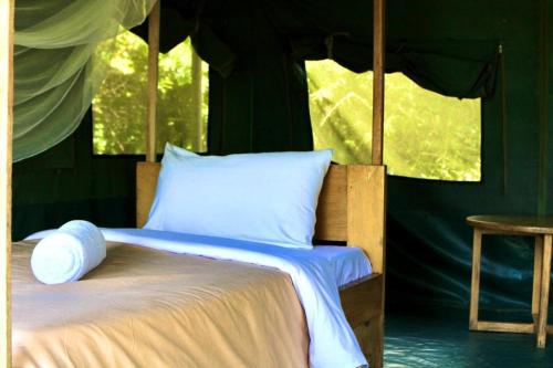 Murchison Giraffe Camp في Murchison Falls National Park: غرفة نوم بسرير في خيمة
