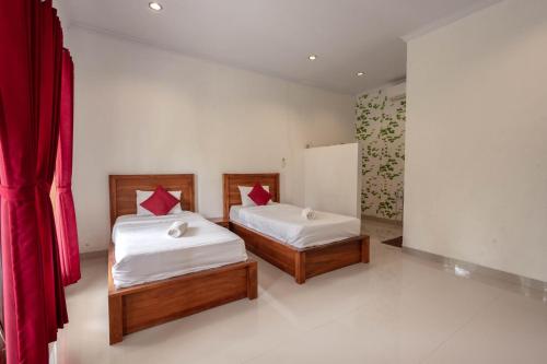 - 2 lits dans une chambre dotée de rideaux rouges dans l'établissement Omah Nusa Villa RedPartner, à Nusa Penida