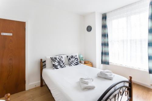 a bedroom with a bed with white sheets and a window at Wood Green Budget Rooms - Next to Mall & Metro Station - 10 Min to City Center in London