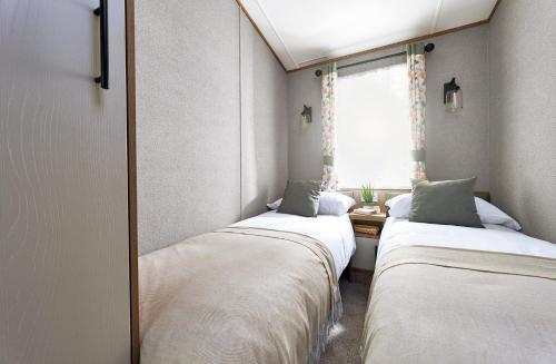 two beds in a small room with a window at Ullswater Holiday Park - Static 5 in Penrith