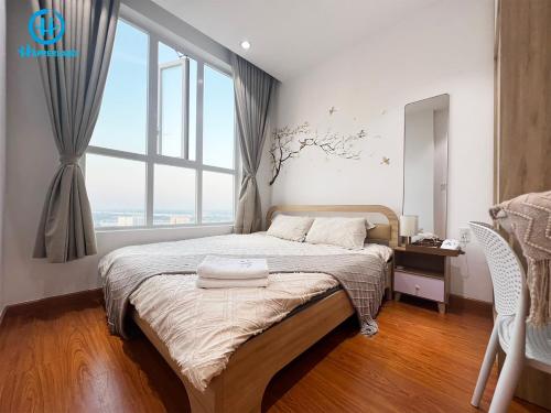 a bedroom with a bed with a large window at Happerland HomeStay Căn hộ Khách sạn 2 phòng Cao cấp Long Xuyên in Long Xuyên