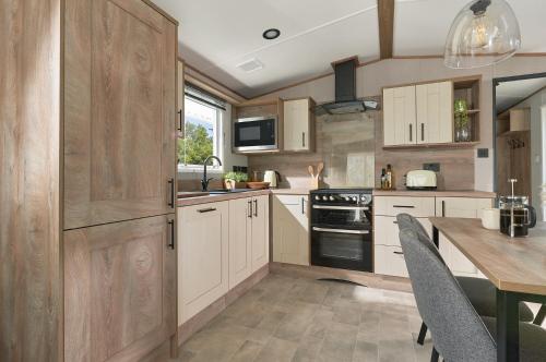 a kitchen with white cabinets and a table with chairs at Ullswater Holiday Park - Static 5 in Penrith