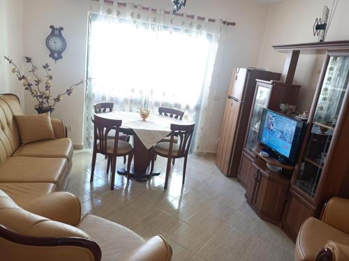 een woonkamer met een tafel en stoelen en een televisie bij AMEL Familiar HOUSE in Durrës