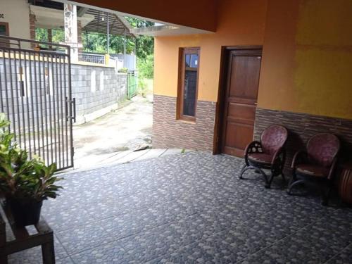 an empty room with two chairs and a door at Agus Homestay in Cibeunjing