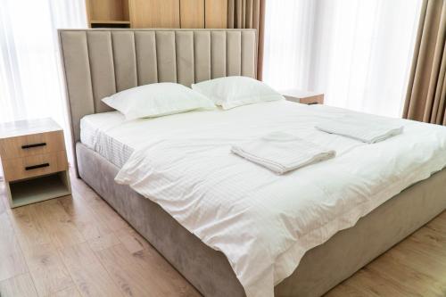 een bed met witte lakens en witte handdoeken erop bij Signature apartment 10 in Tirana