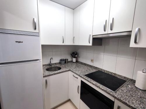 eine Küche mit weißen Schränken und einem Waschbecken in der Unterkunft Mirasierra Suites Pamplona in Pamplona