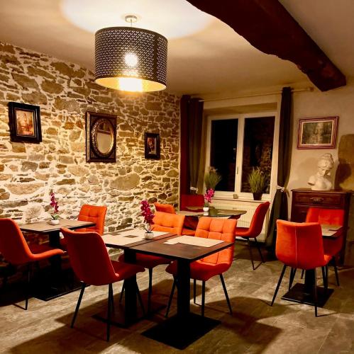 une salle à manger avec des chaises orange et un mur en pierre dans l'établissement Le Manoir des Haies SPA, à Les Champs-Géraux