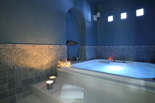 a blue bathroom with a tub with candles and lights at Villa St' Astra in Koufonisia
