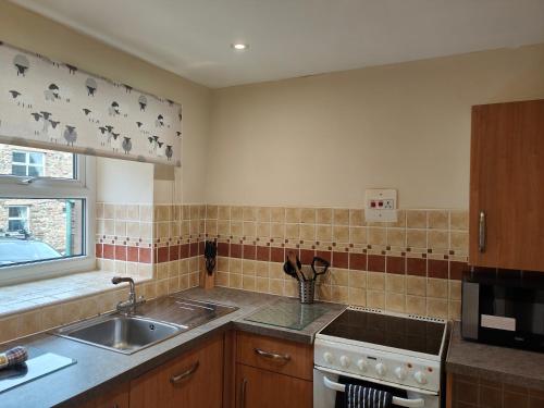 a kitchen with a sink and a stove at Holiday Cottage 4 in Penrith