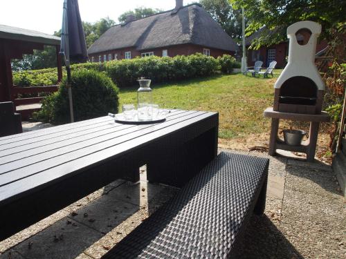 un banc en bois avec une table et un nourrisseur d'oiseaux dans l'établissement Ferienhaus Große Gaarde, à Ockholm