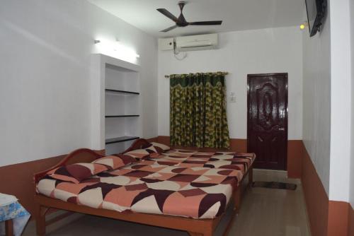 a bedroom with a bed and a ceiling fan at Velānganni Vinodth Homestay in Velankanni