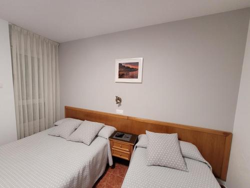 ヒホンにあるHostal San Felixのベッド2台とナイトスタンド付きのホテルルームです。