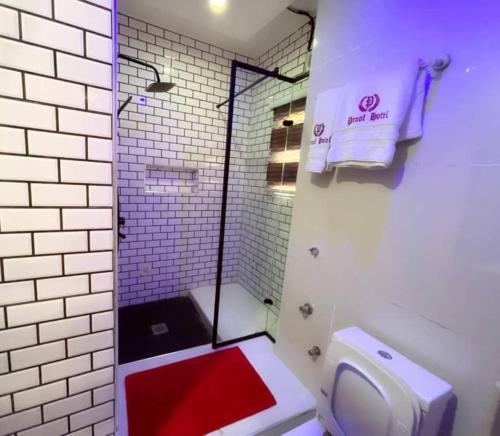 a bathroom with a shower with a toilet and a red floor at Proof Hotel Lekki in Lagos