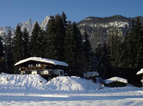 a house covered in snow in front of a mountain at Appartements Wörgötter Astrid & Sepp in Rettenbach