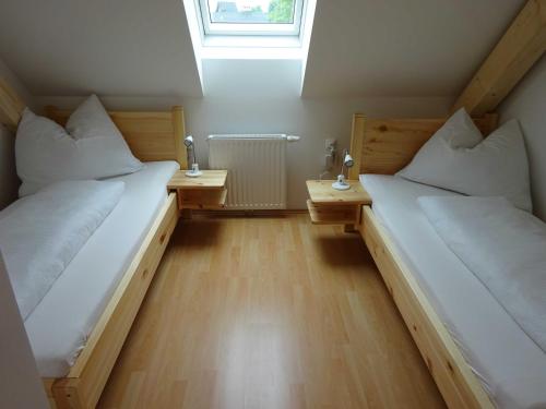 two beds in a room with wooden floors and a window at Ermi Pracher in Groß Sankt Florian