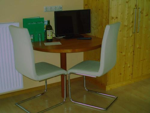 a table with two white chairs and a computer monitor at Ermi Pracher in Groß Sankt Florian
