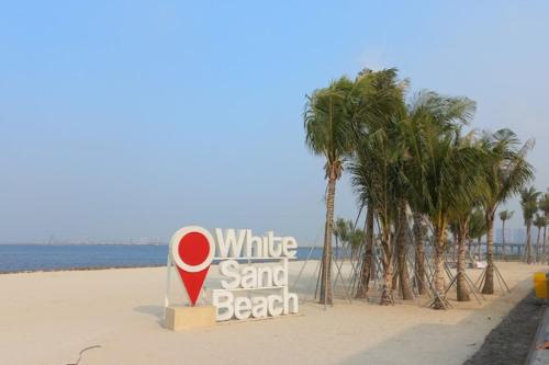 a white sand beach with a sign on the beach at 2BedRooms Apartment in Gold Coast PIK in Jakarta