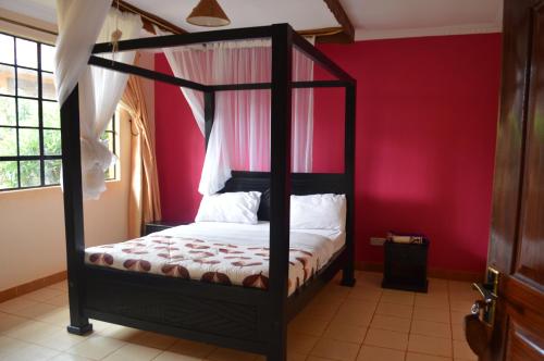 ein Schlafzimmer mit einem schwarzen Himmelbett in einer roten Wand in der Unterkunft jirime hotel &resort in Marsabit