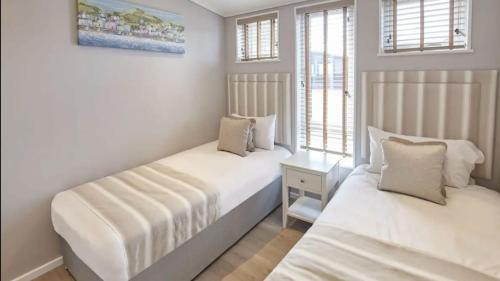 two beds in a room with white walls and windows at Stunning Lodge at Runswick Bay - Dog Friendly in Runswick