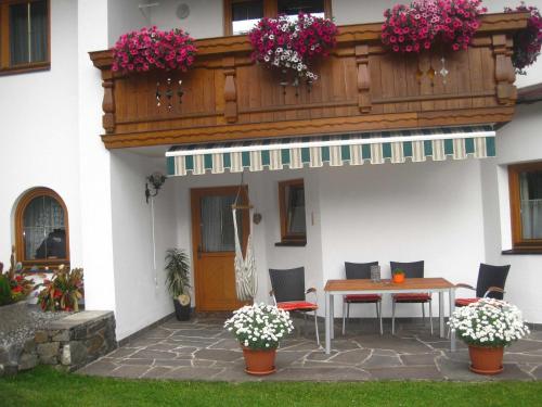a patio with a table and a balcony with flowers at Chalet Sonnblick in Äußere Großrotte