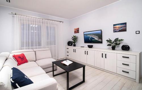 a white living room with a white couch and a tv at Apartament w Helu in Hel