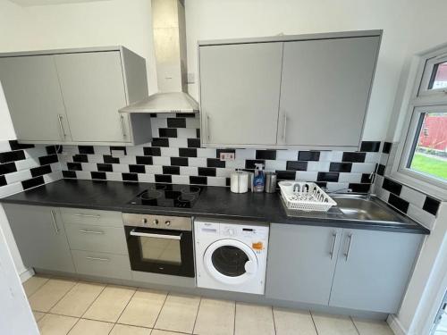 a kitchen with a sink and a washing machine at Whole Flat Close To Wembley in Wealdstone