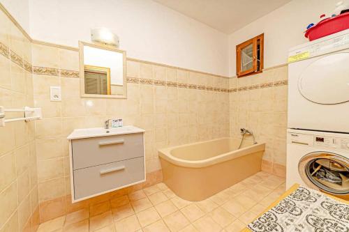 a bathroom with a tub and a washing machine at L'eugénie Le bar-sur-loup in Le Bar-sur-Loup