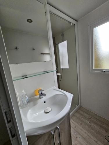 une salle de bain avec un lavabo blanc et un miroir dans l'établissement Grand Mobil Home A114, à Saint-Jean-de-Monts
