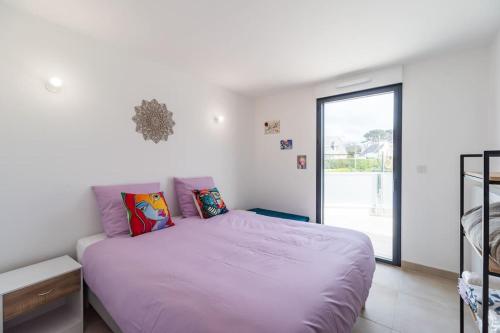 a bedroom with a bed with purple sheets and a window at Appartement neuf Côte de Granit Rose - Ploumanac'h in Perros-Guirec