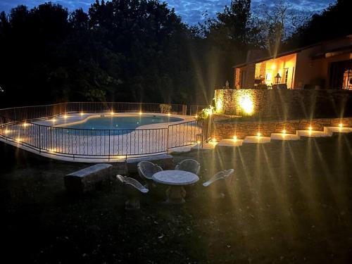 a pool with a table and lights in a yard at Domaine des Figons in Éguilles
