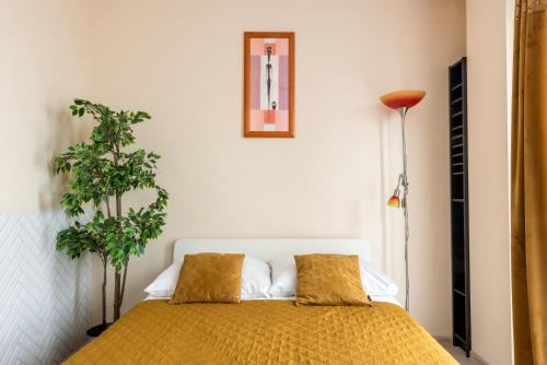 ein Schlafzimmer mit einem Bett mit zwei Kissen und einer Pflanze in der Unterkunft Cozy modern Apartment ASTORIA MAGIC ORANGE OLD TOWN in Krakau