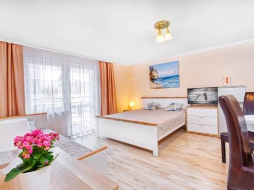 a bedroom with a bed and a table with flowers on it at Willa Muszelka Przy Morzu in Jastarnia