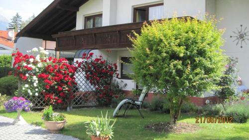 ein Haus mit Blumen und einem Stuhl im Hof in der Unterkunft Appartements Wessely am Golfplatz Lans Innsbruck in Innsbruck