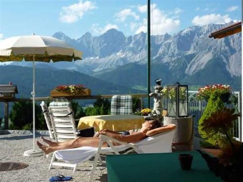 Ein Mann, der auf einer Terrasse mit Bergblick auf Stühlen liegt in der Unterkunft Haus Rigl in Vorberg