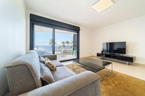 a living room with a couch and a television at L'Horizon- appartement 2 personnes à Bellepierre avec vue sur mer in Saint-Denis