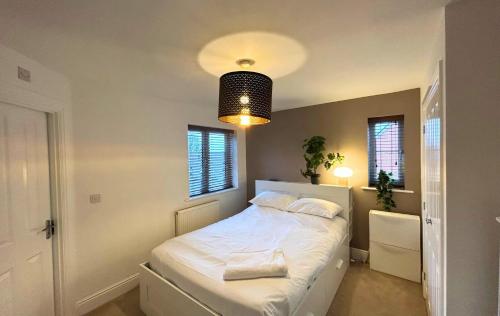 una camera da letto con un letto con lenzuola bianche e una luce di Wokingham Spectacular 2 Bedroom Penthouse a Bracknell