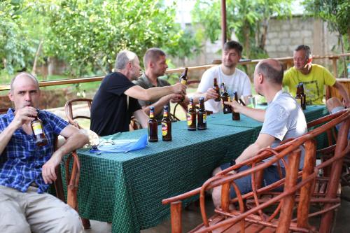 Kilibase Hotel في موشي: مجموعة من الرجال يجلسون على طاولة يشربون البيرة