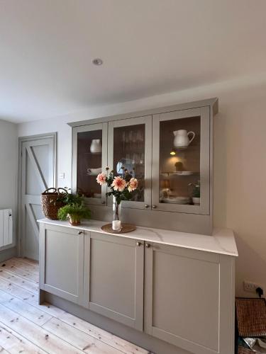 a white cabinet with flowers in a room at Efail Fach in New Quay