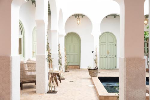 um pátio com portas verdes e uma piscina em Riad Al Uzza em Marraquexe