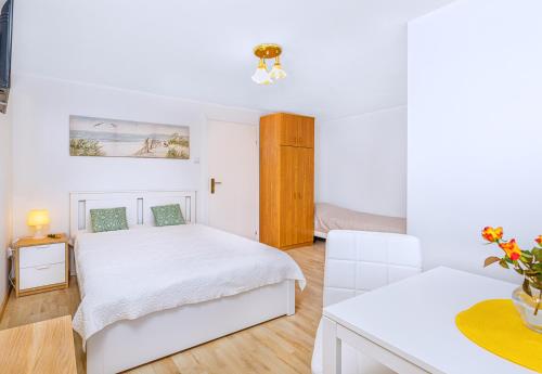 a white bedroom with two beds and a table at Willa Muszelka Przy Morzu in Jastarnia